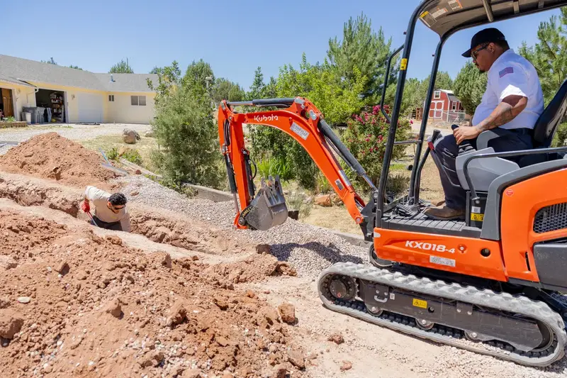 Mini excavator digging a water line trench in St. George, UT